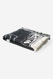 Couverture Letterpress Black/Wax Carhartt WIP, pliée, motif graphique noir et blanc, avec franges.