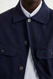 Blouson Worker Marine LATER... sur une chemise rayée, avec des détails de boutons et de poches brodées vertes.