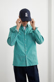 Chemise HEOL Rayures Vertes LATER... portée par un homme ajustant sa casquette marine et ses lunettes de soleil.