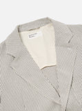 Two Button Jacket Grey Derby Stripe Universal Works portée par un modèle. Coupe moderne et polyvalente, idéale pour un look habillé ou décontracté. À porter avec une chemise et un chino pour un style raffiné, ou avec un t-shirt pour une allure plus décontractée. Disponible en boutique chez SEE YOU à Versailles.