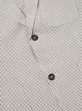 Détail du col classique et de la fermeture à deux boutons de la Two Button Jacket Grey Derby Stripe Universal Works. Finitions soignées et élégantes, parfaites pour une tenue sophistiquée et polyvalente. Disponible en exclusivité chez SEE YOU, concept store à Versailles.