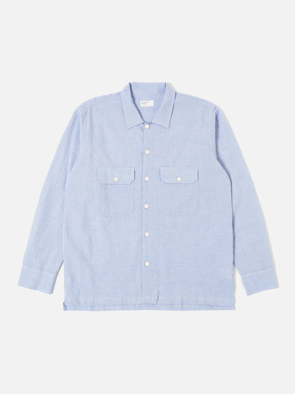 L/S Utility Shirt Pale Blue Seersucker Universal Works, chemise à manches longues inspirée du workwear. Tissu en seersucker léger et texturé, parfait pour un confort optimal et une bonne respirabilité. Coloris bleu pâle élégant et polyvalent. Disponible exclusivement en boutique chez SEE YOU, concept store à Versailles.