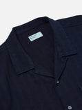 Détail du col ouvert et de la patte de boutonnage de la Road Shirt Indigo Herringbone Denim Universal Works. Finitions minimalistes et boutons discrets pour une élégance sobre. Disponible en exclusivité dans notre concept store à Versailles.