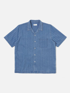 Road Shirt Washed Indigo Herringbone Denim Universal Works, chemise légère en denim à chevrons. Coupe droite et col ouvert pour une allure décontractée et élégante. Teinte indigo délavée, offrant un look vintage et authentique. Disponible dans notre concept store homme à Versailles.