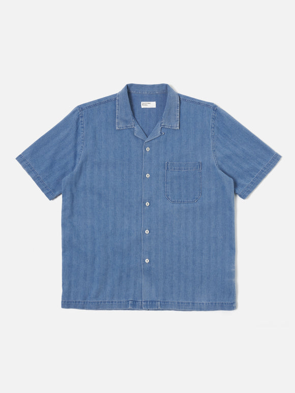 Road Shirt Washed Indigo Herringbone Denim Universal Works, chemise légère en denim à chevrons. Coupe droite et col ouvert pour une allure décontractée et élégante. Teinte indigo délavée, offrant un look vintage et authentique. Disponible dans notre concept store homme à Versailles.