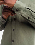 Gros plan sur le tissu de la chemise Décré Taza Vert Olive OLOW. Coton bio de qualité supérieure, doux et agréable au toucher. Coutures solides et finition parfaite pour une chemise durable et confortable.