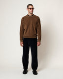 Homme portant le sweatshirt Homecore Aquae Cocoa, un pantalon en velours côtelé foncé et des lunettes de soleil.