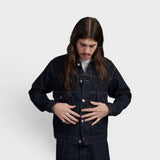 Homme portant une Veste en Jean Rincée Edwin foncée, les mains sur la veste, regardant vers le bas sur fond blanc.