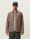 Homme portant une Surchemise en Laine Dark Sand Les Deux, un t-shirt blanc et un pantalon foncé, avec une casquette noire.