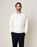 Homme portant le sweatshirt Aquae Ecru HOMECORE, un pull crème à manches longues et un pantalon bleu marine.