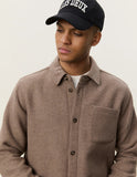 Surchemise en laine Dark Sand Les Deux portée par un homme, avec un t-shirt blanc et une casquette noire.