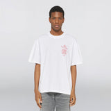 Homme portant un t-shirt Edwin Ekoda Bath House blanc avec un imprimé graphique rouge.