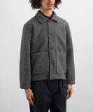 Veste Uniforme Universal Works en laine polaire gris chiné, portée par un homme. Détail des boutons et des poches.