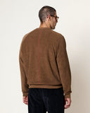 Homme de dos portant un Sweatshirt Aquae Cocoa HOMECORE marron avec bande rouge, et pantalon en velours côtelé bleu marine.