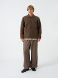 Homme portant la veste Rams en laine polaire marron chiné Universal Works, un pantalon à chevrons marron et des mocassins noirs.