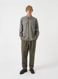 Homme portant le pantalon de survêtement plissé en moleskine brossée olive de Universal Works avec une chemise.