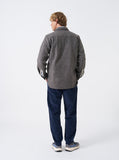 Vue arrière d'un homme portant la chemise de travail Universal Works Work Shirt Dam Marl Marron Chiné et un pantalon bleu.