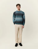 Homme portant le Pull Col Rond Dégradé Mediterranea Green Les Deux, un pantalon en velours côtelé beige et des chaussures noires.