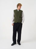 Gilet zippé en polaire de laine vert olive Universal Works porté par un homme avec un pantalon noir. Style décontracté.