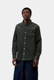 Homme en chemise Carhartt WIP Madison Cord Shirt Raven, velours côtelé vert foncé, coupe classique et boutons blancs.