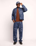 Veste Akka Life Dance Olow, veste en jean bleue avec des motifs abstraits blancs, t-shirt marron et pantalon bleu motifs